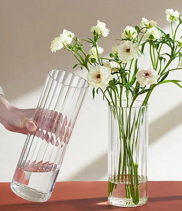 چیدن گل‌های سفید در گلدان شیشه‌ای برای گل آرایی میز