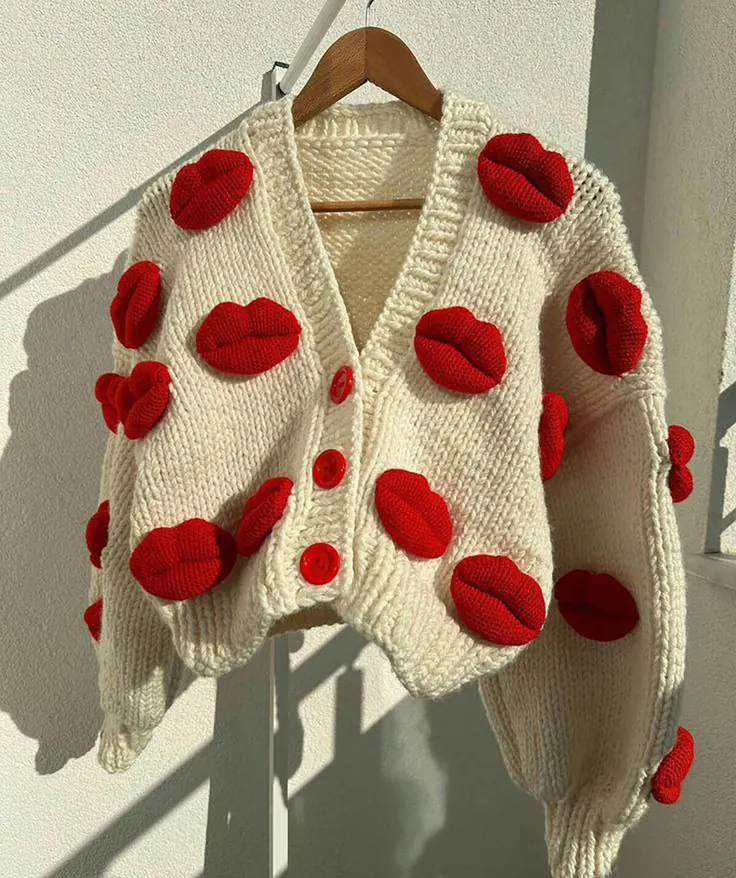 ژاکت بافت سفید با لبه‌های قرمز روی چوب‌لباسی